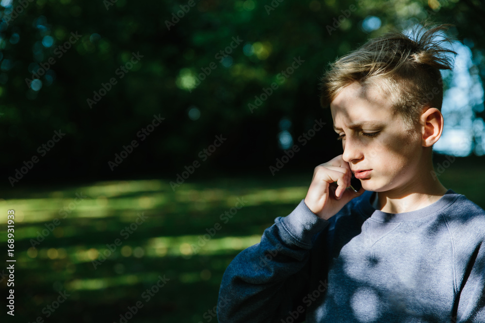 Teenage boy talking on a cell phone outdoors Teenage boy talking on a cell phone outdoors
