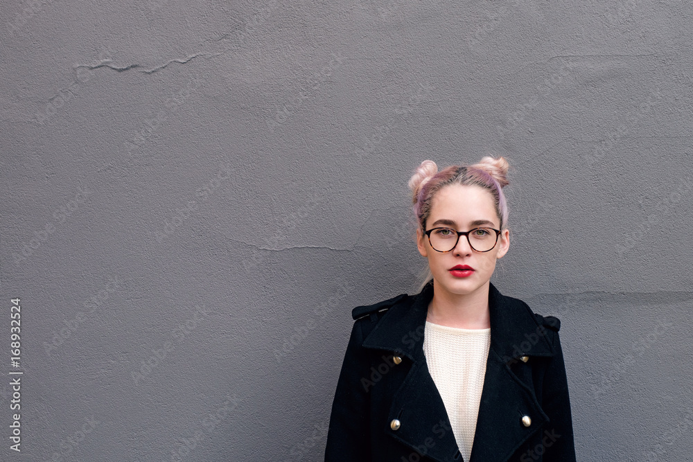 Portrait of teenage girl standing against gray wall Portrait of teenage girl standing against gray wall