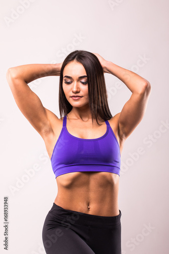 Smiling sports woman standing with arms over head and looking at camera isolated on a white background
