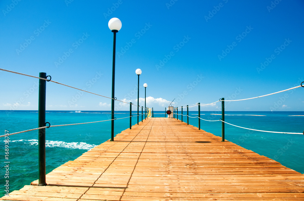 Wooden pier, exotic sea and a blue sky. Beautiful summer background. Vacation and traveling concept.