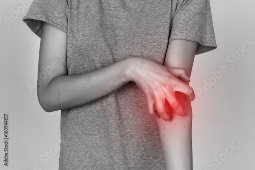 Girl in grey shirt scratching her arm. Scabies. Scratch the hand. Black and white with red accent