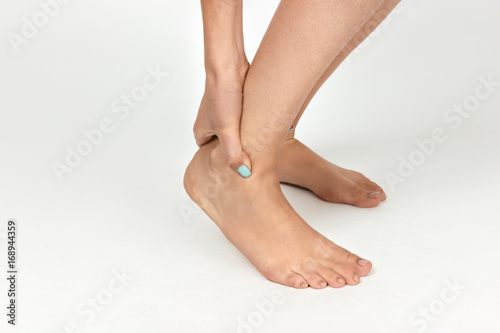 Woman hand holding her beautiful healthy foot and massaging ankle in pain area. Pain concept close-up