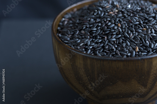 Photos Black rice in a wooden bowl. Closeup.
