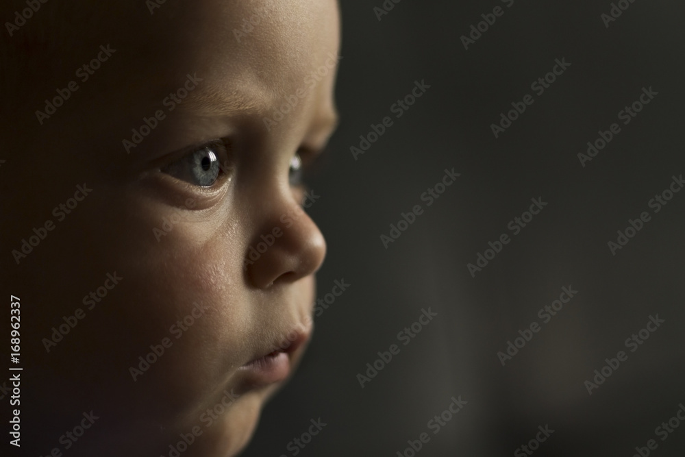 Portrait of serious one year toddler on the dark background. Close-up view. Copy space Portrait of serious one year toddler on the dark background. Close-up view. Copy space