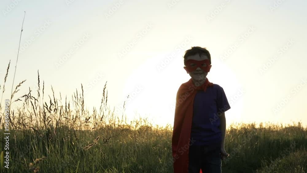 Happy little child playing superhero at the sunset time. Kid having fun outdoors. Concept of boy power. Happy little child playing superhero at the sunset time. Kid having fun outdoors. Concept of boy power.