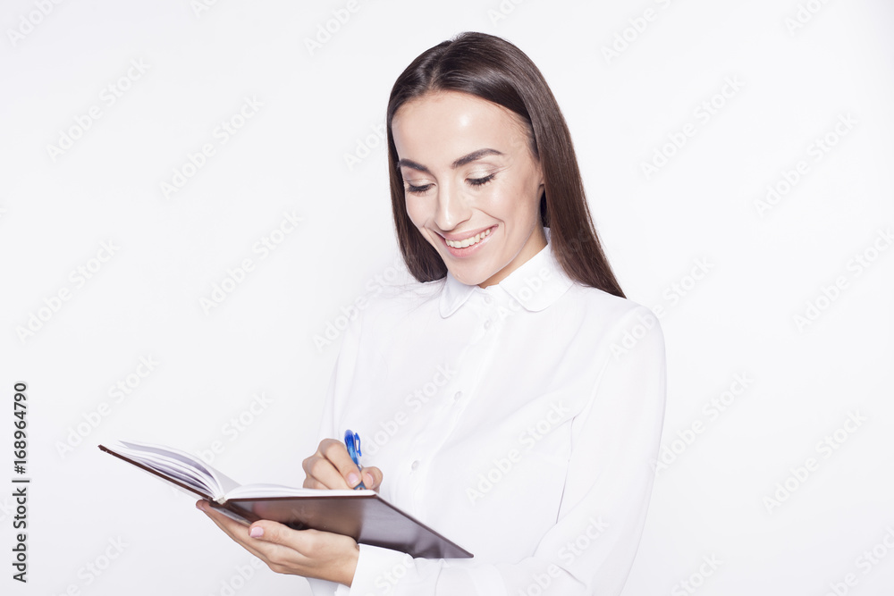 Beautiful brunette Business Woman writes the notes in notebook isolated on white background. Beautiful brunette Business Woman writes the notes in notebook isolated on white background.