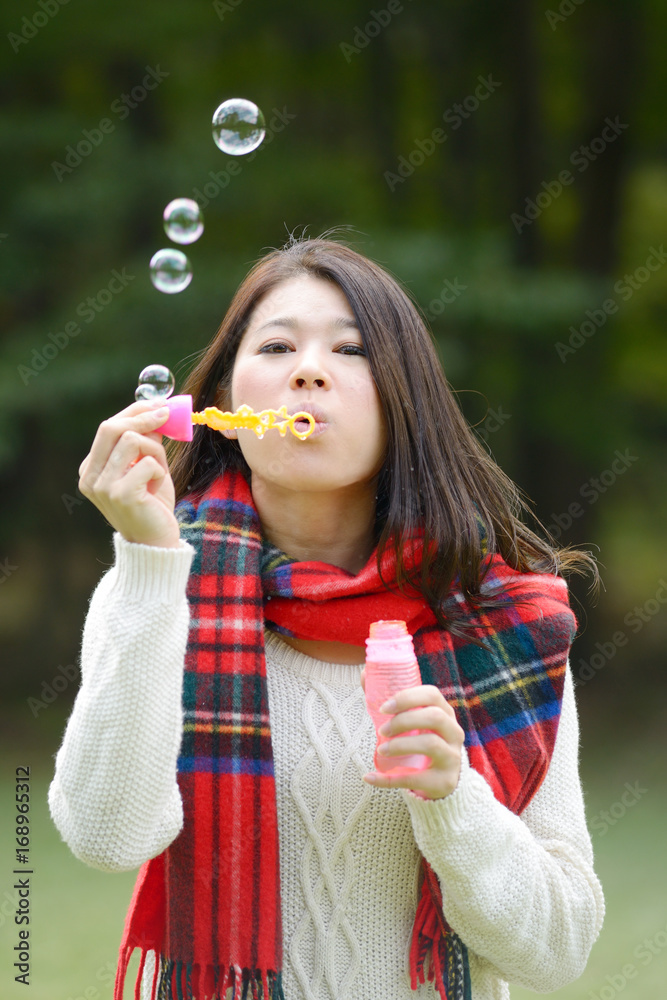 秋の公園でシャボン玉で遊ぶ女性