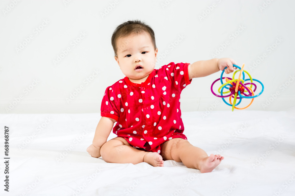 Portrait of adorable infant baby sitting on the white floor and smiling to camera with bites toy Portrait of adorable infant baby sitting on the white floor and smiling to camera with bites toy