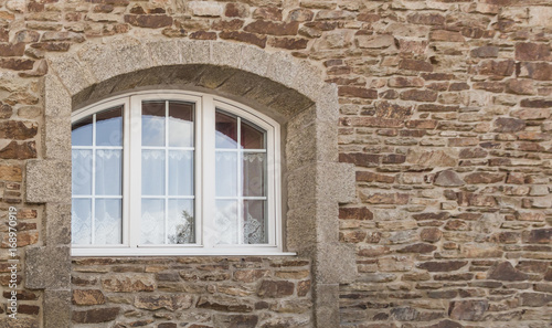 Schönes Bogenfenster aus weißem PVC mit 3 Flügeln in Fassade aus Naturstein in Granit - Beautiful arched window in white PVC with 3 wings in natural stone facade in granite