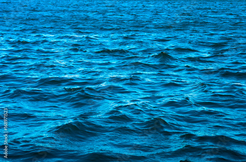 The sea is blue, with small waves on a bright sunny day.