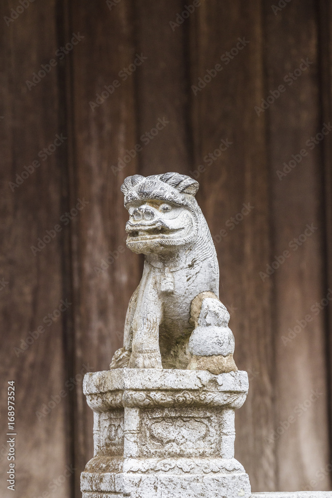 BAC NINH, VIETNAM - JULY 25, 2015 - Small statue at the entrance to But Thap Pagoda with a demon or lion on a decorated pedestal with a flower motif