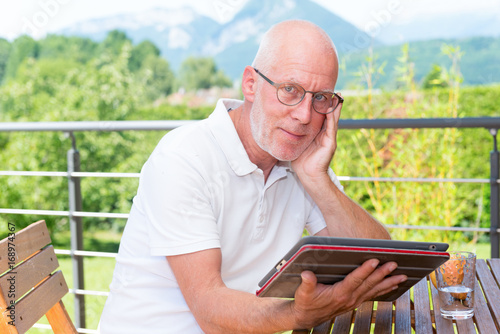 mature man using tablet  computer on the terrace,