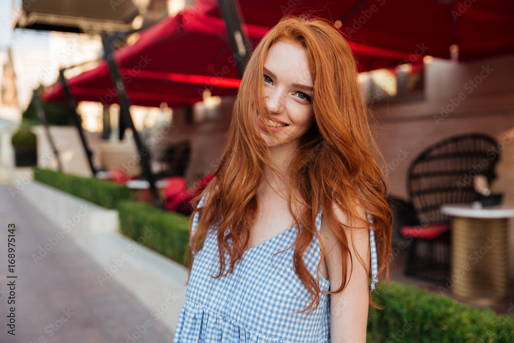 Smiling pretty redhead girl with long hair looking at camera