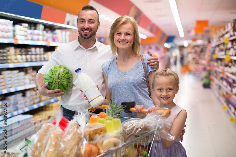 Adult parents with child shopping in hypermarket