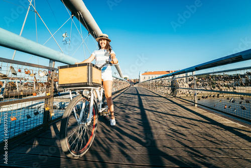 Fotografija pretty woman riding bicycle on the bridge