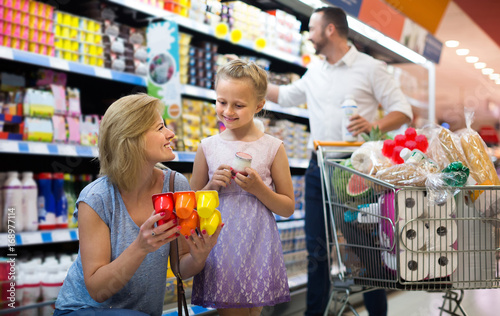 Portrait of woman and girl holding package with yogurt in grocery shop