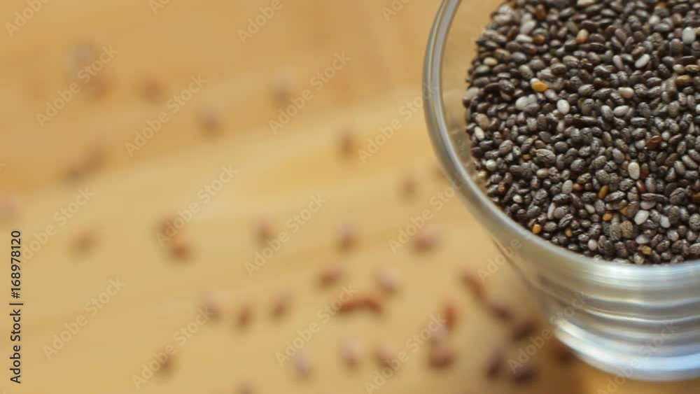 Healthy chia seeds in glass bowl on wooden table. Macro top view