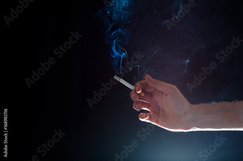 hand holding a smoky cigarette in a dark atmosphere