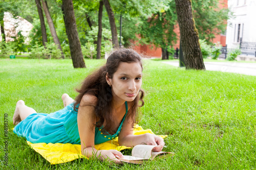 Brunette girl resting with a book on the lawn © Beliakina Ekaterina