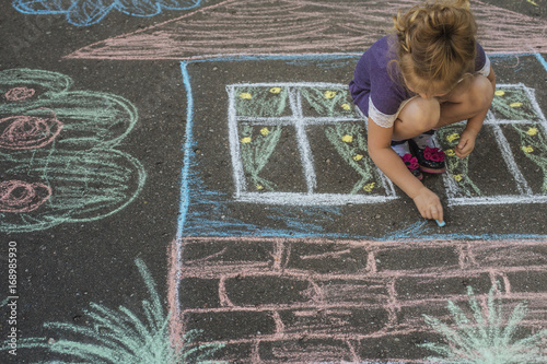 Girl draw house with chalk on asphalt