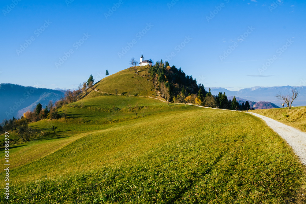 Hikers on the road to the church of St. Jakob on Petelinec hill near Medvode