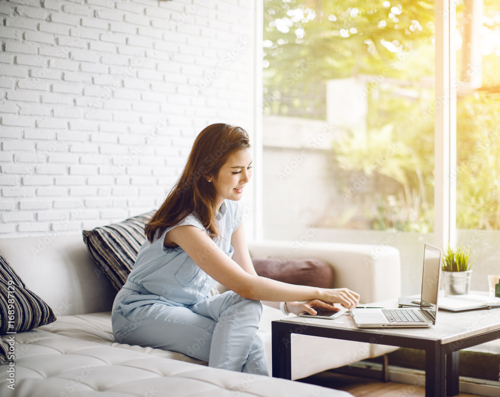 Beautiful Young Asia Woman On A Sofa Working With A Laptop at home Beautiful Young Asia Woman On A Sofa Working With A Laptop at home