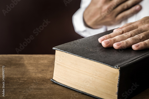 Man's hand swearing on the bible. Taking an oath.  photo