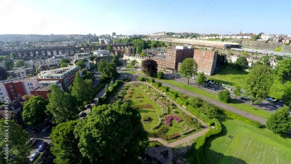 Aerial cityscape from above park with sea behind - A vertical climb from a city park in Brighton, England revealing a view of the city with the sea in the background. A train passes over a viaduct. Aerial cityscape from above park with sea behind - A vertical climb from a city park in Brighton, England revealing a view of the city with the sea in the background. A train passes over a viaduct.