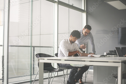 Two business men working together in office. Reading document.