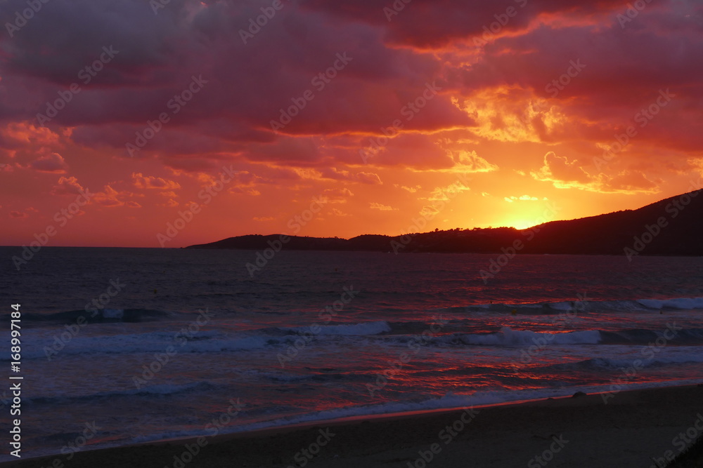 Fototapeta premium Coucher de soleil sur la plage avec un ciel nuageux : rougeur vive