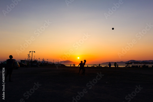 Silhouetted shot of young people are having fun on beach and playing football