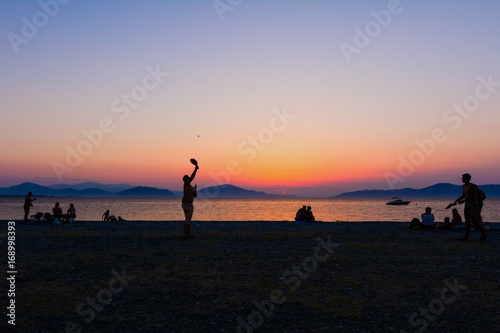 Silhouetted shot of young people playing beach tennis