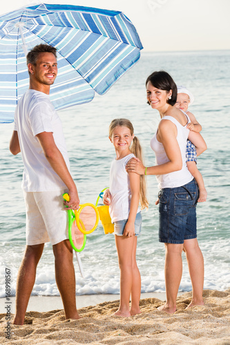 family under sun umbrella on the beach.