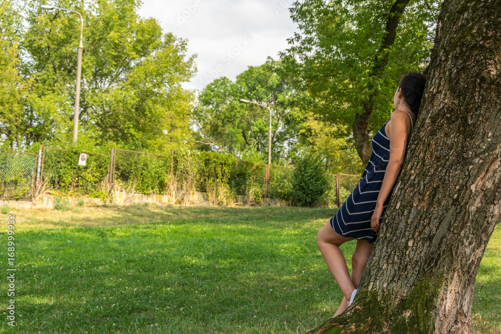 Young woman standing by the tree in park