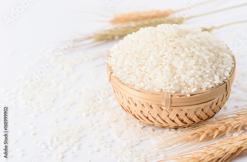 raw rice in a bamboo basket with wheat isolated on white background