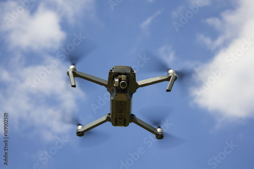 The drone flying over the blue sky background to take a photo / The flying drone on the sky