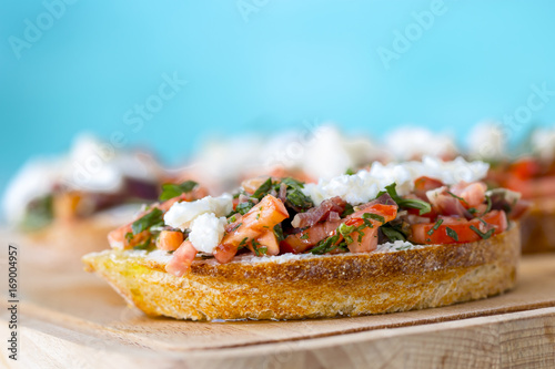 Bruschetta with tomato, cheese and olive oil on a blue background