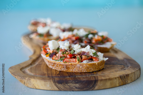 Bruschetta with tomato, cheese and olive oil on a blue background