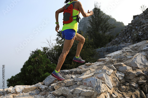 trail runner woman running at great wall on the top of mountain