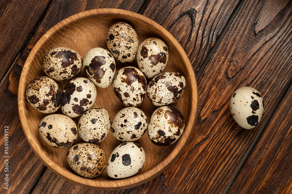 top view on quail eggs in wooden plate over old wooden background top view on quail eggs in wooden plate over old wooden background
