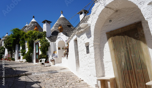 ALBEROBELLO  ITALY - JULY 31  2017  Beautiful street of Alberobello with trulli houses among green plants and flowers  main touristic district  Apulia region  Southern Italy