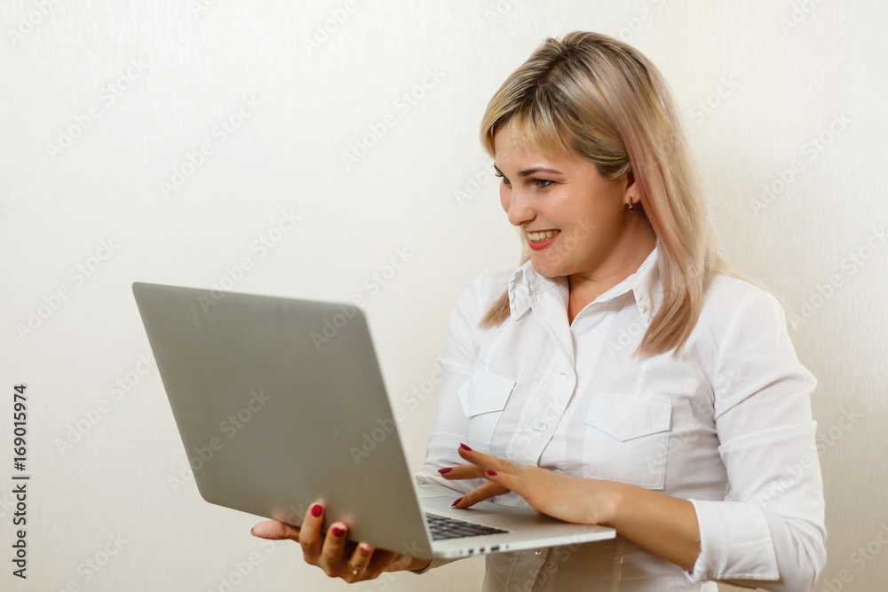 Smiling lovely young businesswoman standing and holding laptop over white background Smiling lovely young businesswoman standing and holding laptop over white background