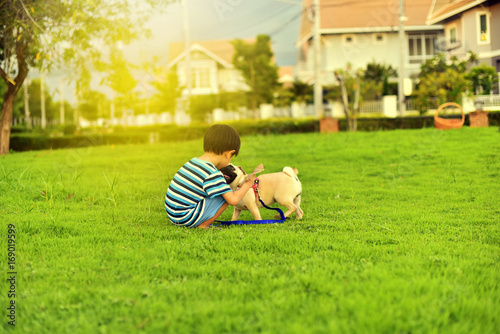 Happy Asian boy playing with his dog in garden