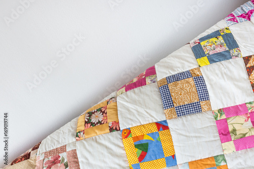 coziness, vintage, retro concept. part of quilled scrappy blanket with brigth-colored ornament represented by yellow, blue and pink squares falls off gradient from sofa