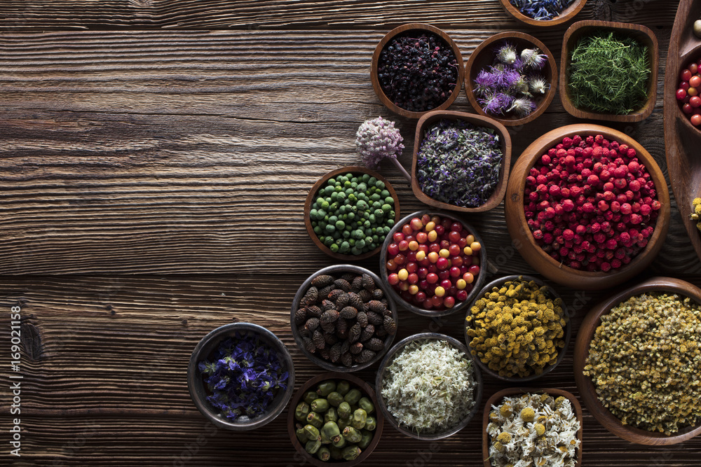 Alternative medicine. Wooden table, shallow depth of focus. Mortar, berries, flowers and herbs assorted in bowls. Alternative medicine. Wooden table, shallow depth of focus. Mortar, berries, flowers and herbs assorted in bowls.