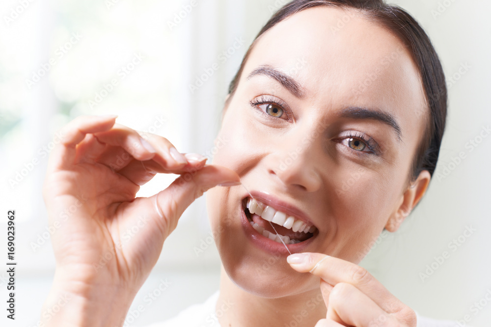 Woman  In Bathroom Flossing White Teeth