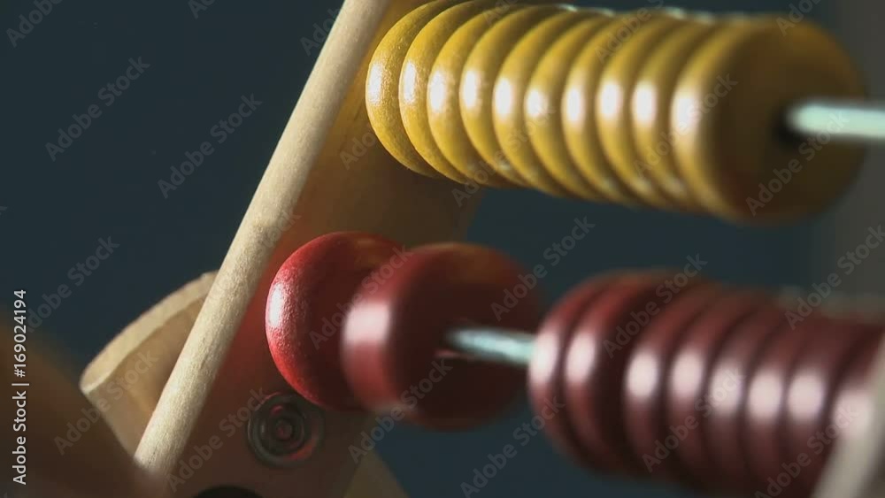 Man's hands doing the math and counting the cost moving yellow and red abacus balls close up Man's hands doing the math and counting the cost moving yellow and red abacus balls close up