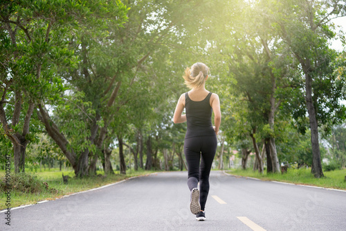 Young fitness sport woman running on the road in the morning, Sun light flare , Selective focus.