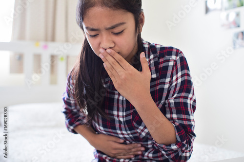 Young Girl Sitting On Bed At Home Feeling Nauseous photo