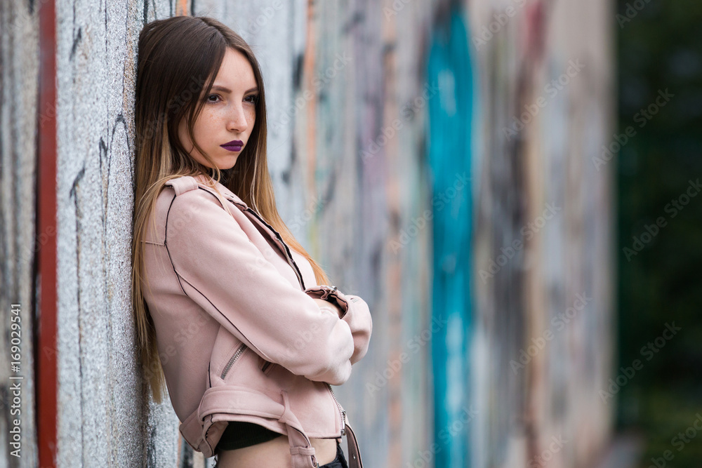 Naklejka premium Portrait of informal fashionable girl on graffiti wall background